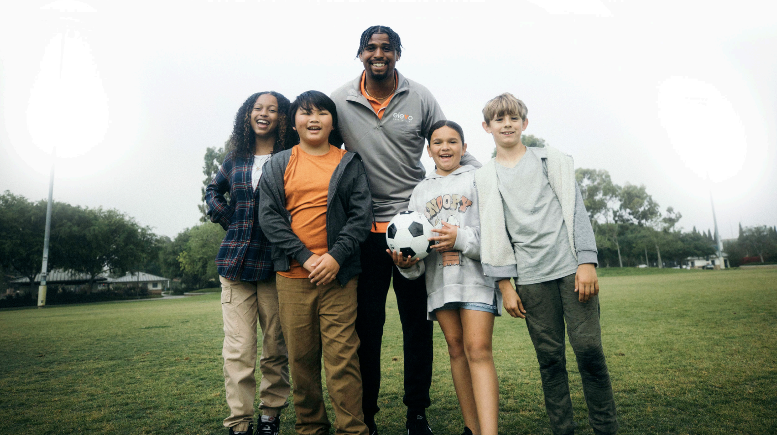 Group of students and teacher or instructor from Elevo Learning playing soccer
